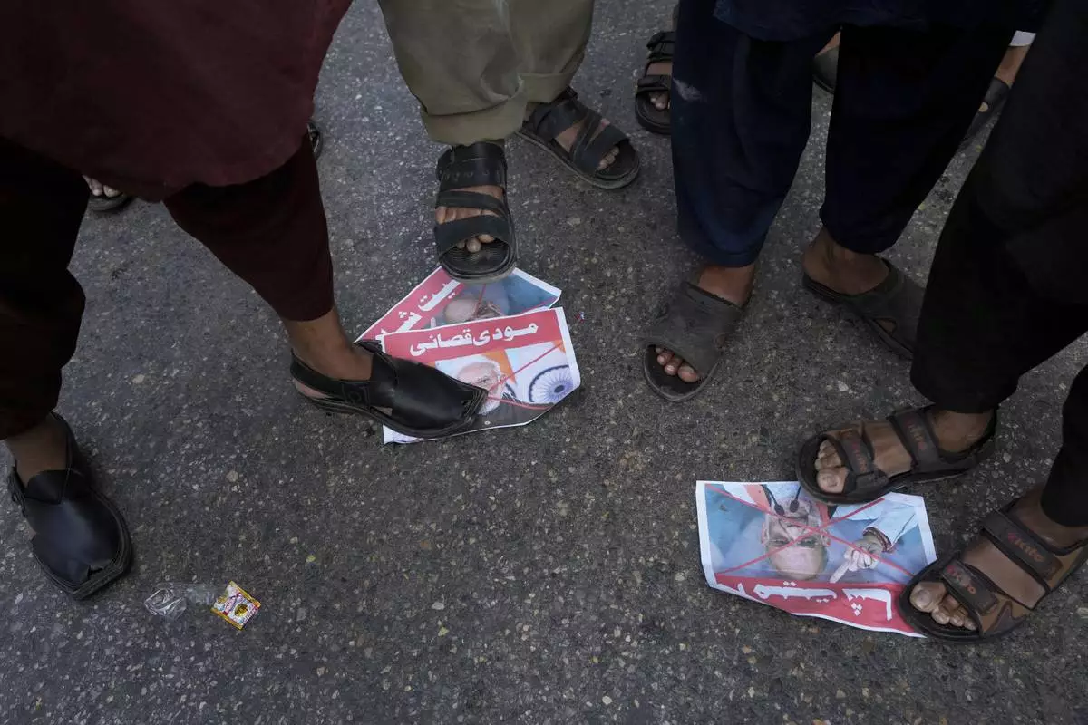 Supporters of the Pakistan Murkazi Muslim League party stand over the crossed posters of Indian Prime Minister Narendra Modi and Indian Minister of Home Affairs Amir Shah during a demonstration against the suspension of water-sharing treaty by India with Pakistan, in Karachi, Pakistan Thursday, April 24, 2025. (AP Photo/Fareed Khan)