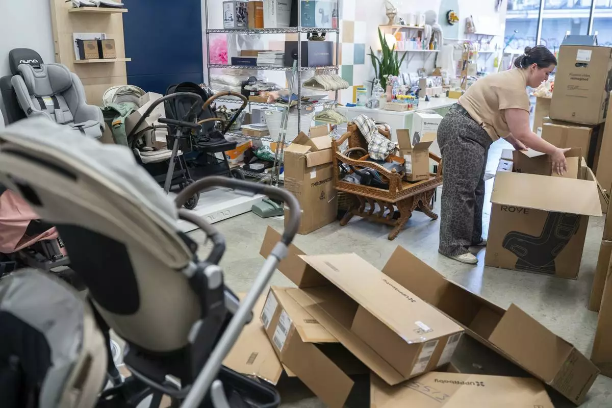 Sales associate Charlotte Santoli unpacks strollers and other inventory ordered by customers ahead of tariff-driven price increases at the Union Market location in Washington, on Wednesday, April 16, 2025. (AP Photo/Nathan Howard)