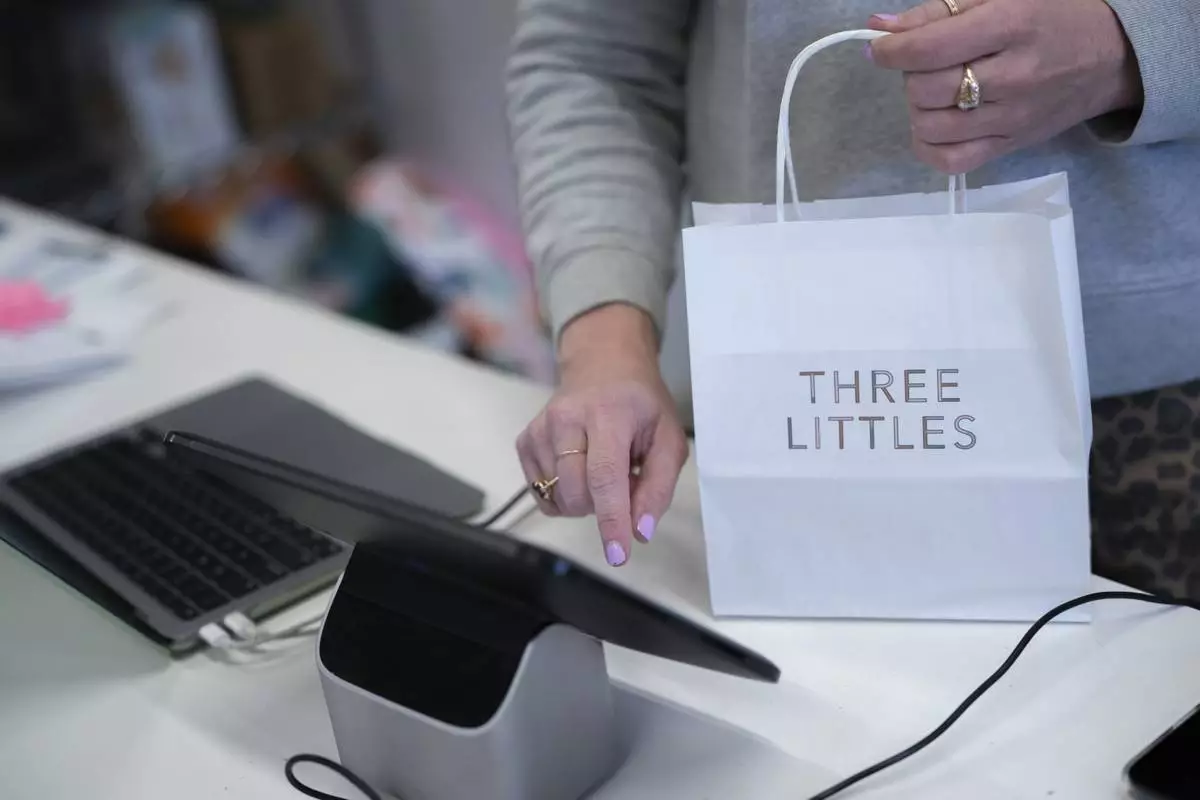 Elizabeth Mahon, owner of the baby store Three Littles, rings up a customer at her Union Market location in Washington, on Wednesday, April 16, 2025. (AP Photo/Nathan Howard)