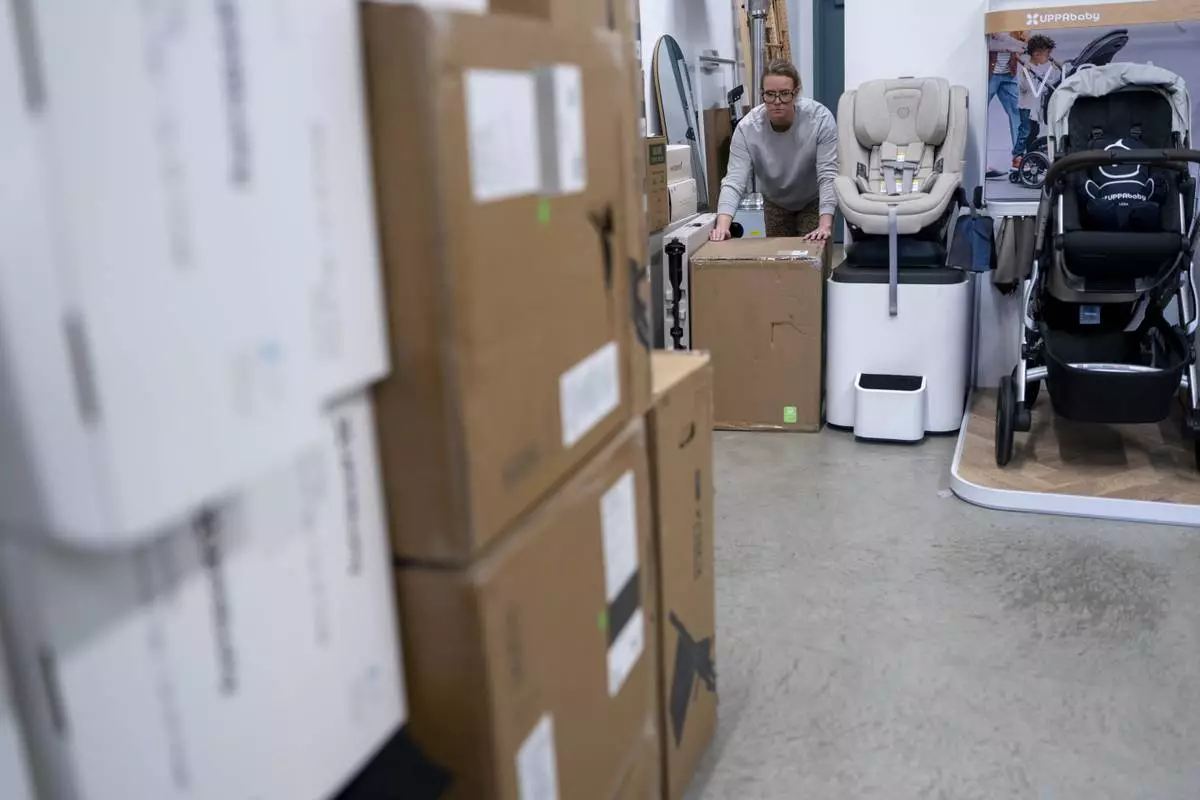 Elizabeth Mahon, owner of the baby store Three Littles, unpacks strollers and other inventory ordered by customers ahead of tariff-driven price increases at her Union Market location in Washington, on Wednesday, April 16, 2025. (AP Photo/Nathan Howard)