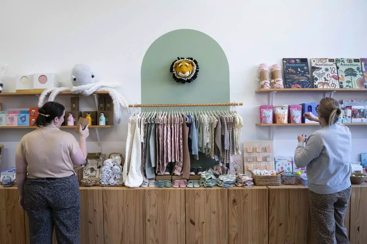 Elizabeth Mahon, right, owner of the baby store Three Littles, and sales associate Charlotte Santoli search through inventory for "Made in China" stickers at the Union Market location in Washington, on Wednesday, April 16, 2025. (AP Photo/Nathan Howard)