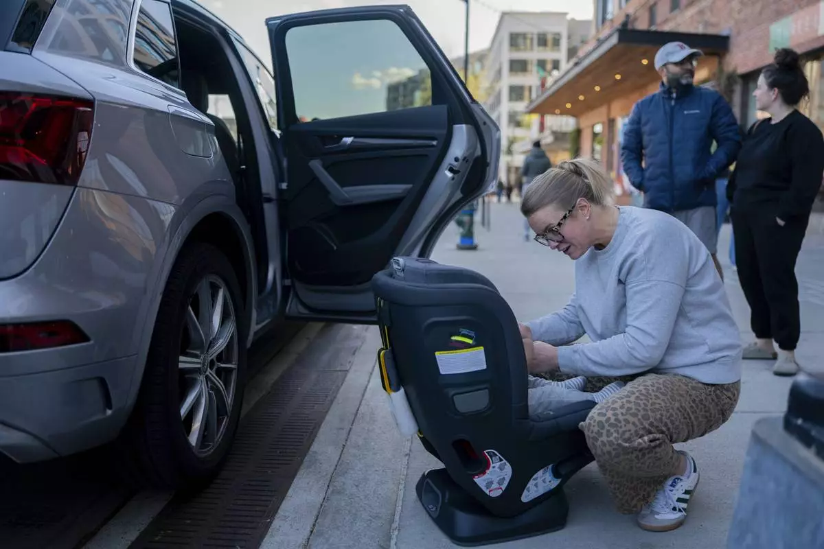 Elizabeth Mahon, owner of the baby store Three Littles, installs a new car seat for customers who made the purchase ahead of tarriff-driven price increases, at the Union Market location in Washington, on Wednesday, April 16, 2025. (AP Photo/Nathan Howard)