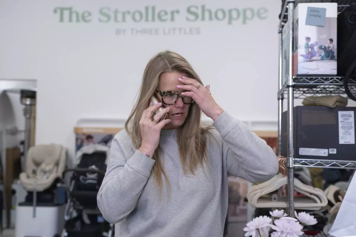Elizabeth Mahon, owner of the baby store Three Littles, explains tariff-driven price increases to a caller searching for stroller recommendations at her Union Market location in Washington, on Wednesday, April 16, 2025. (AP Photo/Nathan Howard)