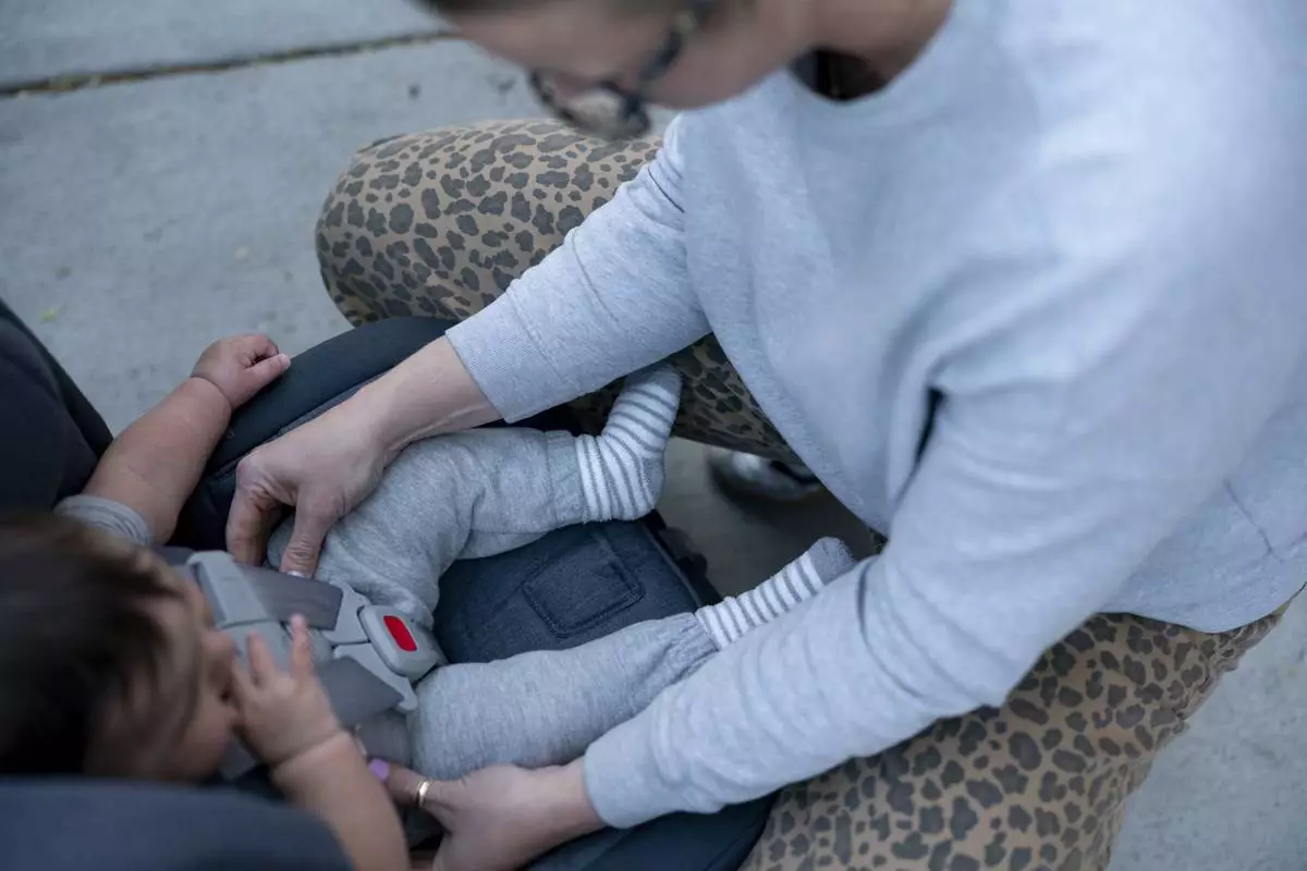Elizabeth Mahon, owner of the baby store Three Littles, installs a new car seat for customers who made the purchase ahead of tarriff-driven price increases in Washington, on Wednesday, April 16, 2025. (AP Photo/Nathan Howard)