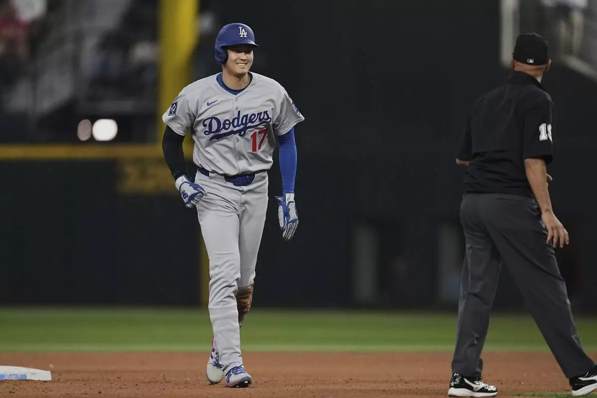 Los Angeles Dodgers' Shohei Ohtani walks to the dugout past umpire Vic Carapazza after a Teoscar Hernandez fly out in the eighth inning of a baseball game against the Texas Rangers in Arlington, Texas, Sunday, April 20, 2025. (AP Photo/Tony Gutierrez)