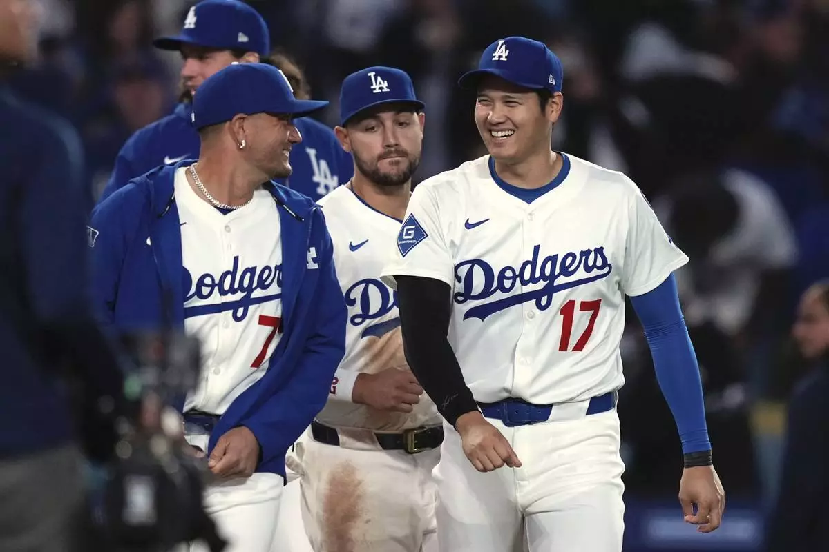 Los Angeles Dodgers' Miguel Rojas, left, and Shohei Ohtani chat after the Los Angeles Dodgers defeated the Colorado Rockies 8-7 in a baseball game Wednesday, April 16, 2025, in Los Angeles. (AP Photo/Mark J. Terrill)
