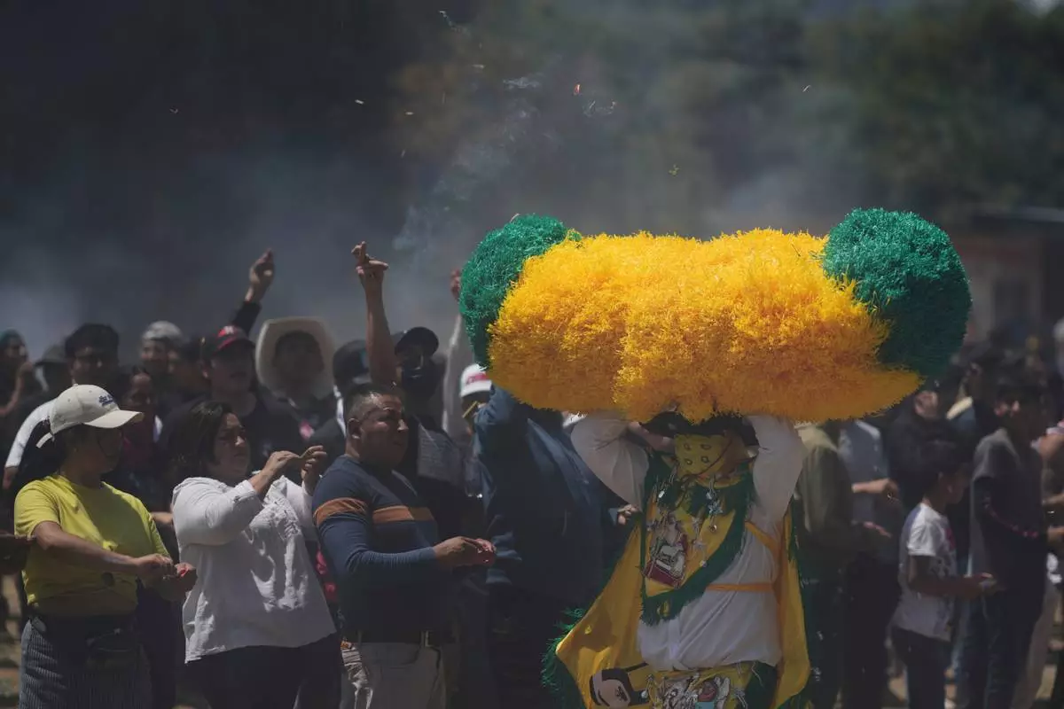 A reveler, known as a sayon, runs with a tissue paper hat as onlookers throw lit matches at him during Easter celebrations in Tetela del Volcan, Mexico, Sunday, April 20, 2025. (AP Photo/Eduardo Verdugo)