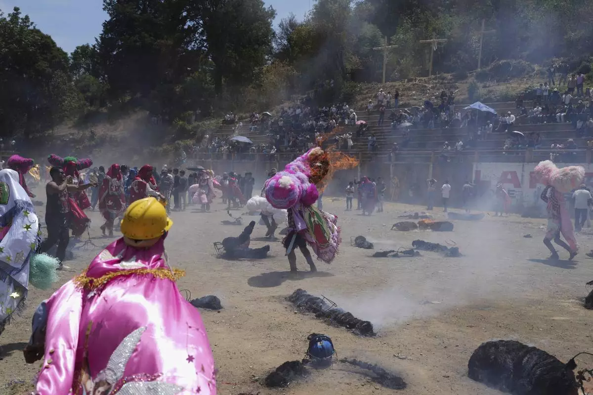 A reveler, known as a sayon, tries to put out a fire he started on his tissue paper hat as part of Easter celebrations in Tetela del Volcan, Mexico, Sunday, April 20, 2025. (AP Photo/Eduardo Verdugo)