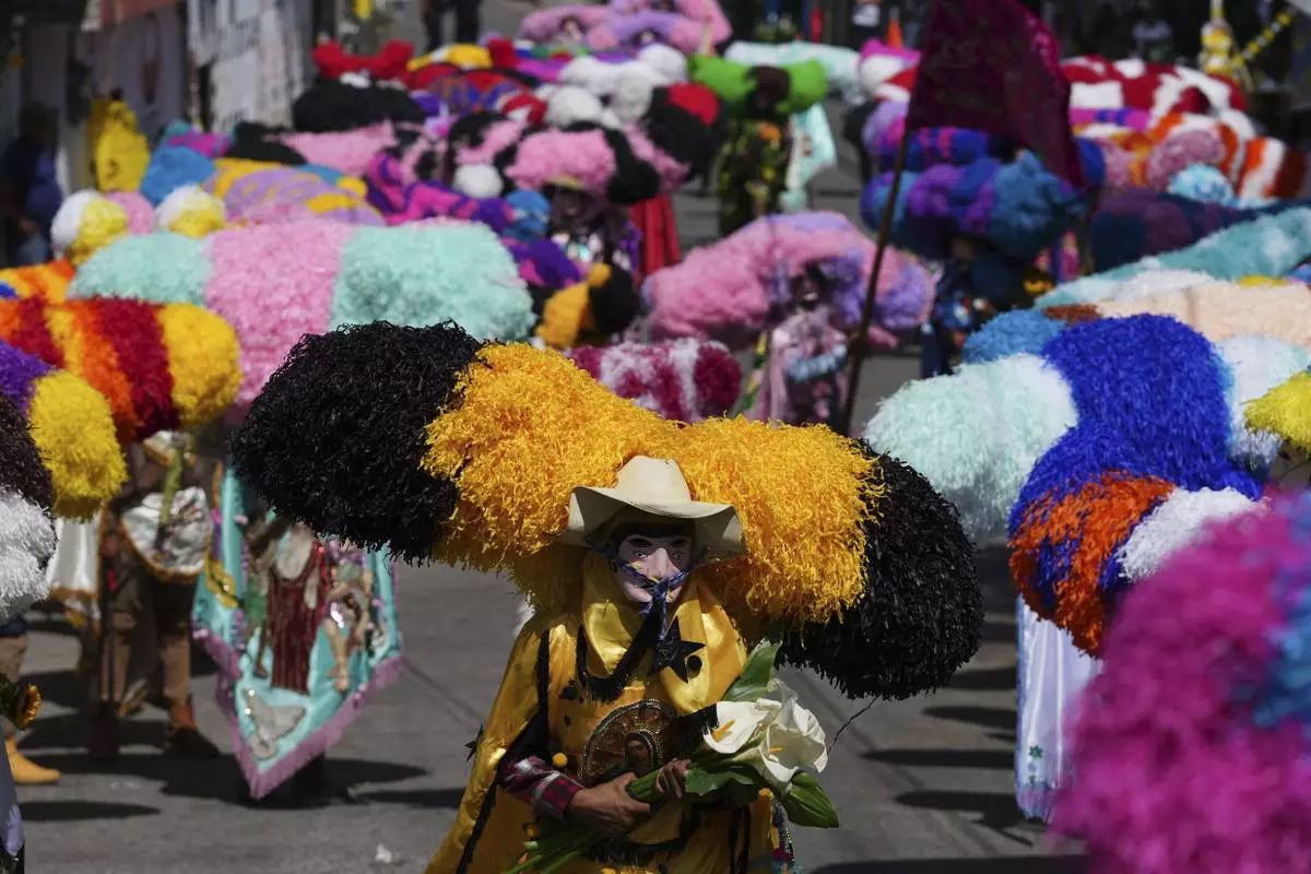 Revelers, known as sayones, wear tissue paper hats during an Easter celebration, in Tetela del Volcan, Mexico, Sunday, April 20, 2025. (AP Photo/Eduardo Verdugo)