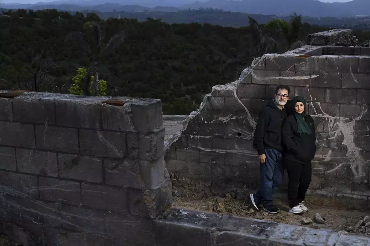 Hatim Naim and his wife Samah stand in a shell of what was their house after it burned in the Mountain Fire Wednesday, April 16, 2025, in Somis, Calif. (AP Photo/Wally Skalij)