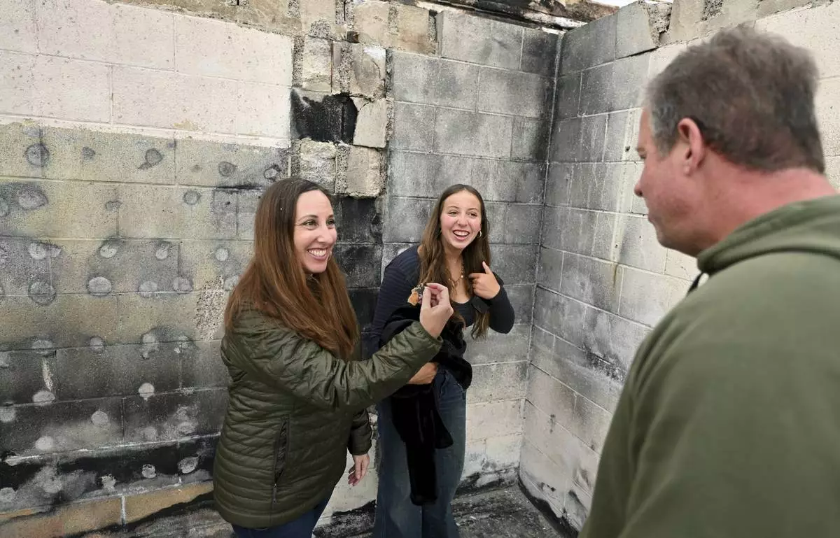 Rachel McNett, left, finds a piece of her old passport as daughter Teagan and husband Keith look on as they visit there house that burned in the Mountain Fire Wednesday, April 16, 2025, in Camarillo, Calif. (AP Photo/Wally Skalij)