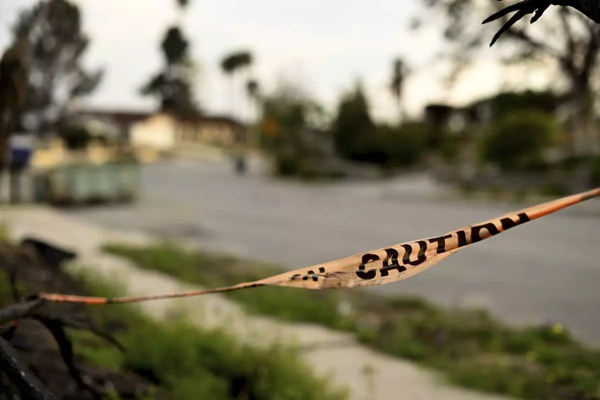 Caution tape hangs on a branch along Old Coach Drive after the Mountain Fire burned through the area Wednesday, April 16, 2025, in Camarillo, Calif. (AP Photo/Wally Skalij)