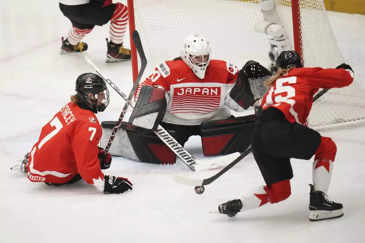 Japan's Miyuu Masuhara, center, makes a save against Daryl Watts of Canada, right, and Laura Stacey of Canada during the quarterfinal match between Canada and Japan at the Women's Ice Hockey Championships in Ceske Budejovice, Czech Republic, Thursday, April 17, 2025. (AP Photo/Petr David Josek)