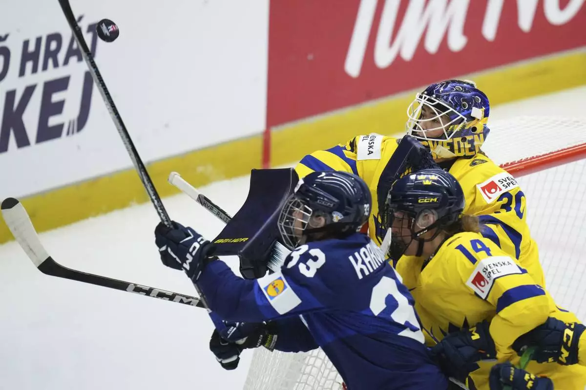 Sweden's Emma Soderberg, right, makes a save during the quarterfinal match between Finland and Sweden at the Women's Ice Hockey Championships in Ceske Budejovice, Czech Republic, Thursday, April 17, 2025. (AP Photo/Petr David Josek)