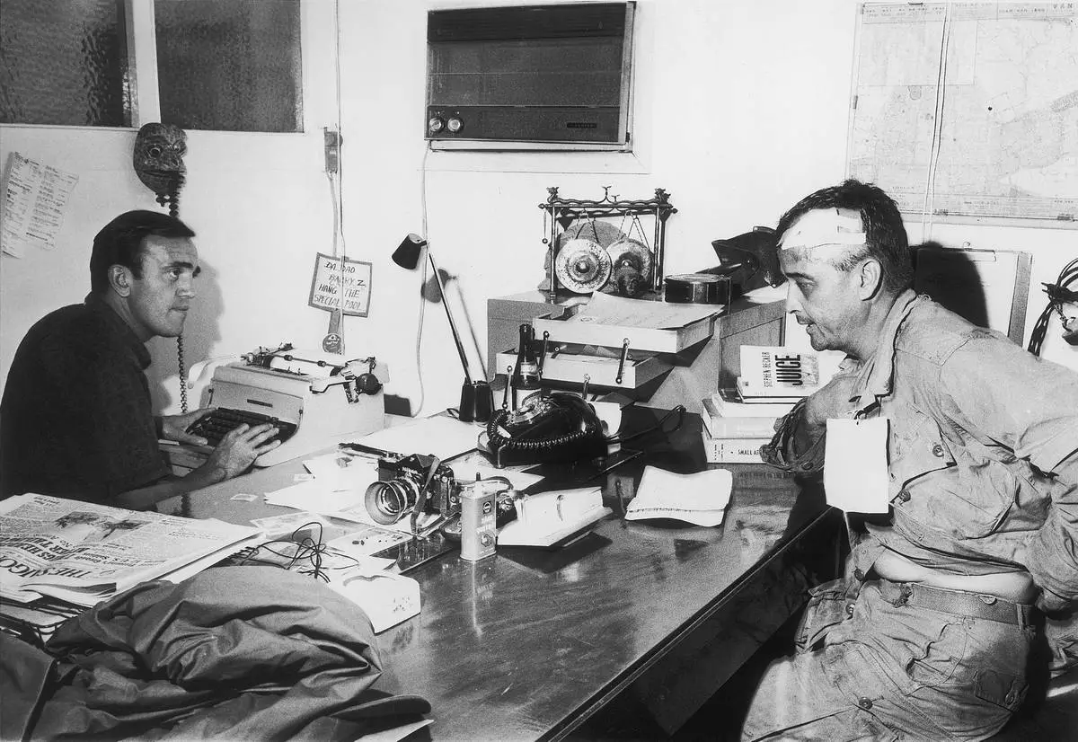 Wounded Associated Press photographer Al Chang gives an account of the battle in which he was injured at Bien Hoa, to AP correspondent Peter Arnett in Saigon, Dec. 1965. Chang was wounded Dec. 18 in a fight with Viet Cong in which five paratroopers died. (AP PhotoAP Corporate Archives)