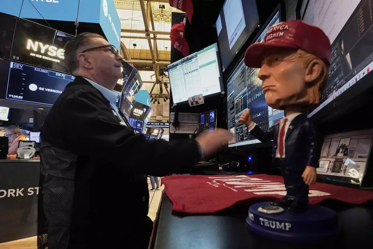 A Donald Trump bobblehead sits on the counter as trader Jonathan Mueller works on the floor of the New York Stock Exchange, Tuesday, April 22, 2025. (AP Photo/Richard Drew)