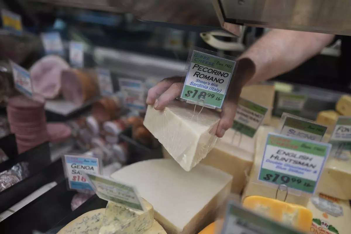 Jeff Gibbs, owner of Gibbs Cheese, reaches for Pecorino Romano cheese imported from Sardinia, Italy, at his shop in Findlay Market, Thursday, April 3, 2025, in Cincinnati. (AP Photo/Carolyn Kaster)