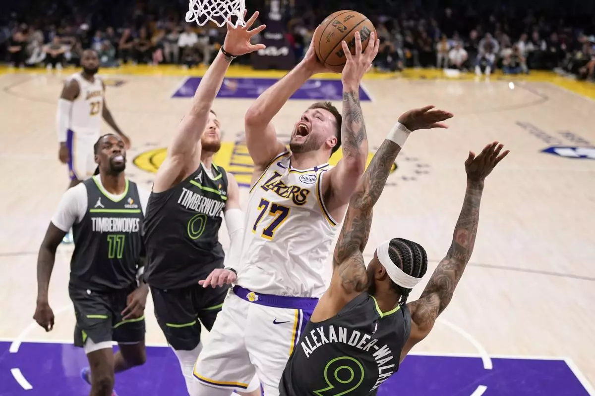 Los Angeles Lakers guard Luka Doncic (77) shoots as Minnesota Timberwolves guard Nickeil Alexander-Walker (9), guard Donte DiVincenzo (0) and center Naz Reid (11) defend during the second half in Game 1 of an NBA first-round playoff series Saturday, April 19, 2025, in Los Angeles. (AP Photo/Mark J. Terrill)