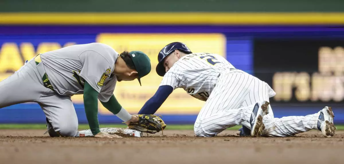 Milwaukee Brewers' Brice Turang, right, steals second base as the Athletics' Luis Urias applies the late tag during the second inning of a baseball game, Sunday, April 20, 2025, in Milwaukee. (AP Photo/Jeffrey Phelps)
