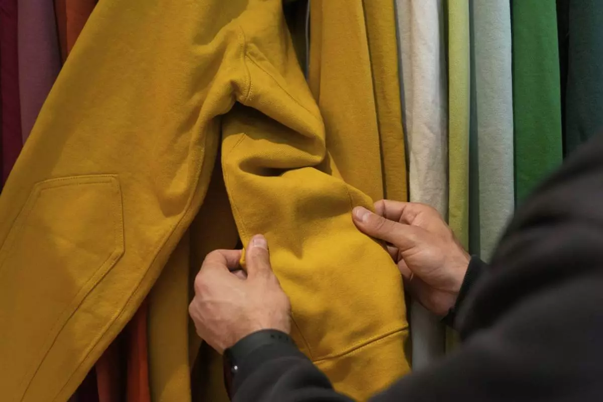 Javid Moghaddasnia, Director of Customer Engagement, holds the sleeve to an American Giant hoodie while being interviewed at the company's showroom in San Francisco, Thursday, April 17, 2025. (AP Photo/Jeff Chiu)