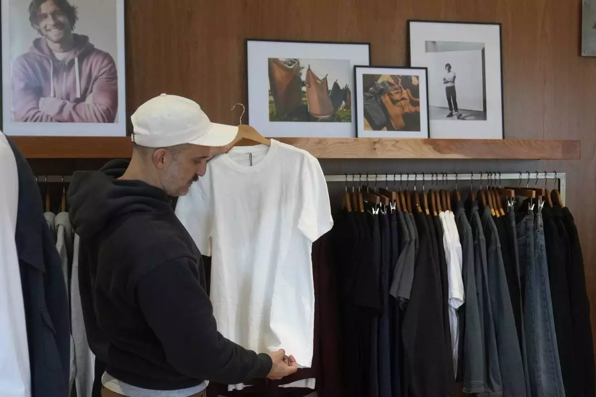 Javid Moghaddasnia, Director of Customer Engagement, holds up an American Giant shirt while being interviewed at the company's showroom in San Francisco, Thursday, April 17, 2025. (AP Photo/Jeff Chiu)