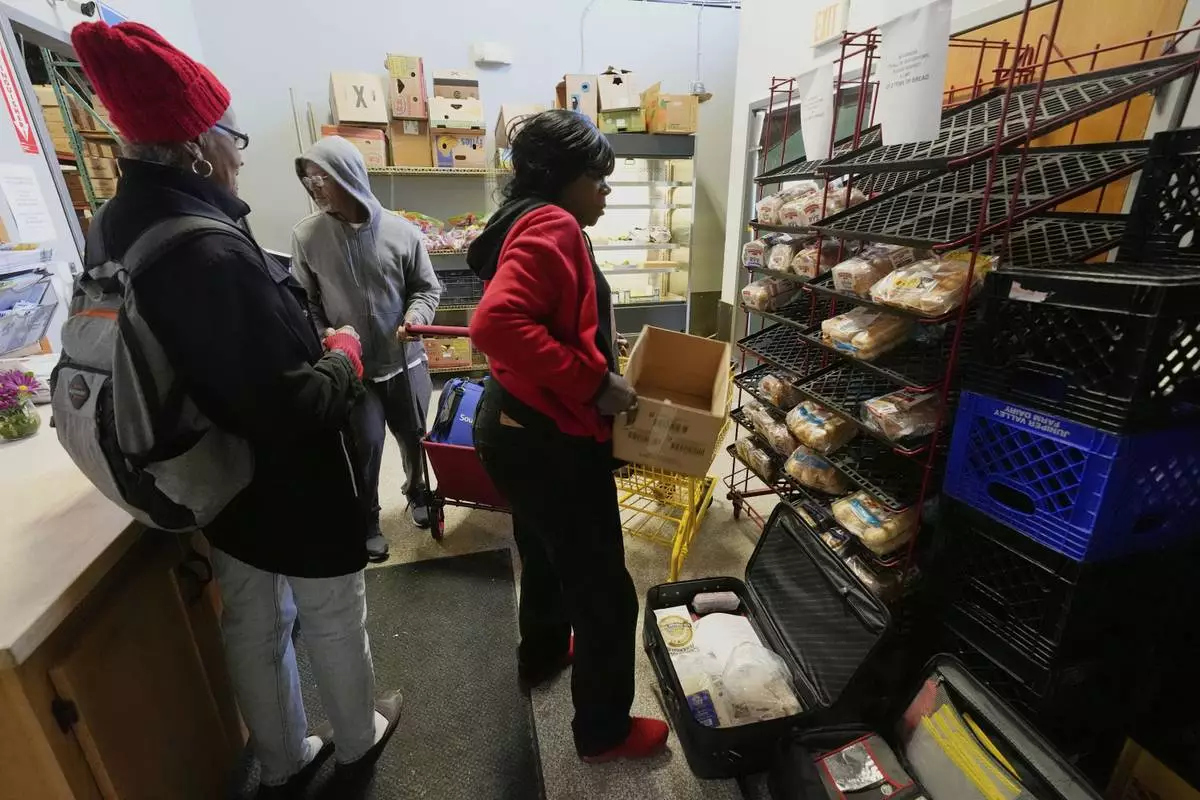 People collect food staples at the Bishop Sullivan Center food pantry, Tuesday, April 15, 2025, in Kansas City, Mo. (AP Photo/Charlie Riedel)