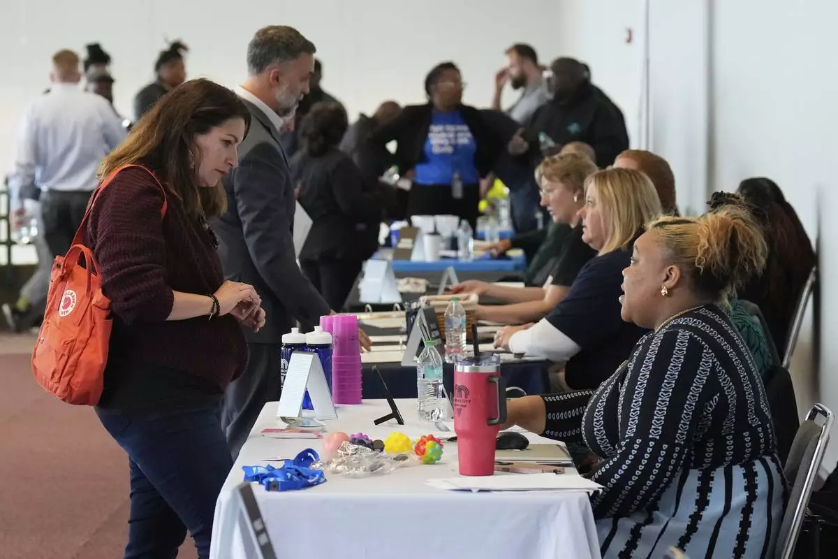 Shea Giagnorio, left, talks to a recruiter at a job fair on the day she was laid off from her job at the Administration for Children and Families, Tuesday, April 1, 2025, in Kansas City, Mo. (AP Photo/Charlie Riedel)