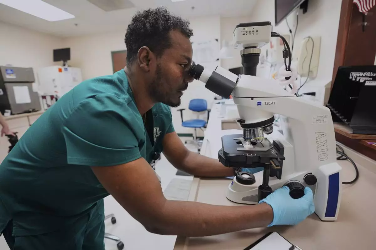Laboratory technician Asfaw Ayana examines a sample at the Kansas City Department of Public Health, Wednesday, April 9, 2025, in Kansas City, Mo. (AP Photo/Charlie Riedel)