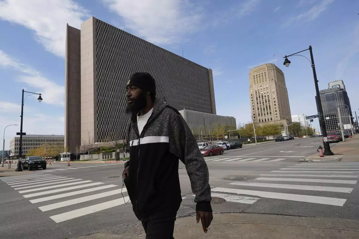 A pedestrian walks past the The Richard Bolling federal building, left, Monday, April 14, 2025, in Kansas City, Mo. (AP Photo/Charlie Riedel)