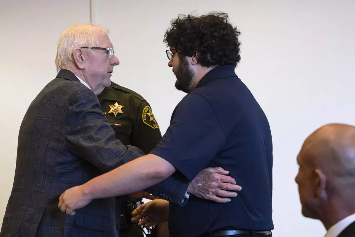 An Orange County Superior Court jury found Orange County Superior Judge Jeffrey Ferguson, left, guilty of second-degree murder in the 2023 shooting death of his wife Sheryl Ferguson, and after he embraced his son, Phillip Ferguson, before being led away in handcuffs Tuesday, April 22, 2025, in Santa Ana, Calif. (Mindy Schauer/The Orange County Register via AP, Pool)
