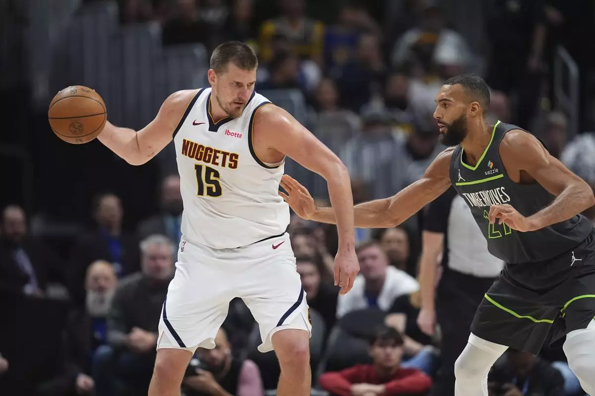 Denver Nuggets center Nikola Jokic, left, looks to pass the ball as Minnesota Timberwolves center Rudy Gobert defends in the second half of an NBA basketball game Tuesday, April 1, 2025, in Denver. (AP Photo/David Zalubowski)