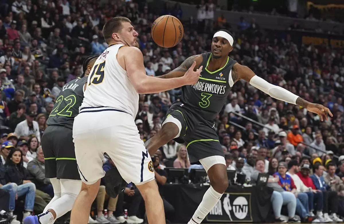 Denver Nuggets center Nikola Jokic, left, pursues a loose ball with Minnesota Timberwolves forward Jaden McDaniels in the second half of an NBA basketball game Tuesday, April 1, 2025, in Denver. (AP Photo/David Zalubowski)