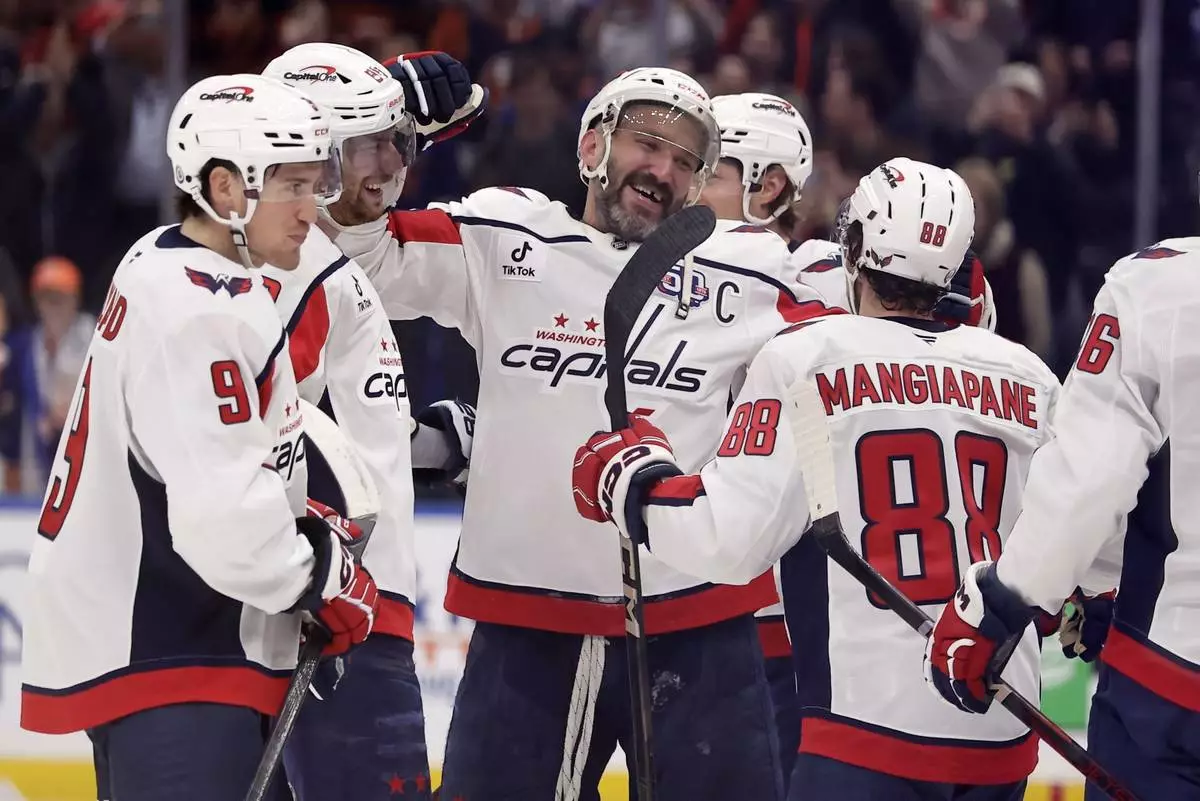 Washington Capitals left wing Alex Ovechkin, center, celebrates with teammates after scoring his 895th career goal during the second period of an NHL hockey game against the New York Islanders, in Elmont, N.Y., April 6, 2025. (AP Photo/Adam Hunger)