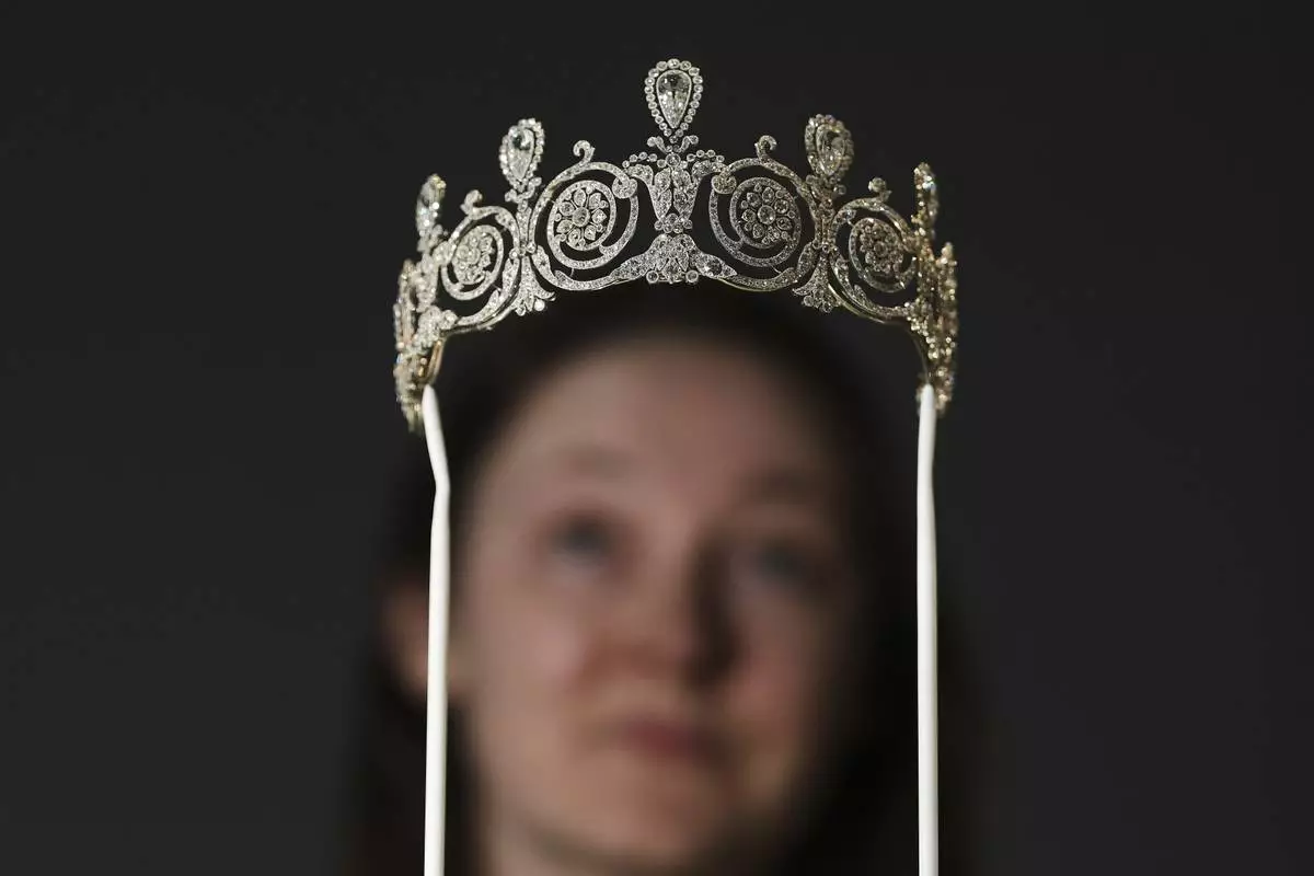 A museum employee looks at a tiara on display at Cartier – the first major exhibition in almost 30 years dedicated to Cartier jewels and watches, at the V&amp;A Museum in London, April 9, 2025. (AP Photo/Kirsty Wigglesworth)