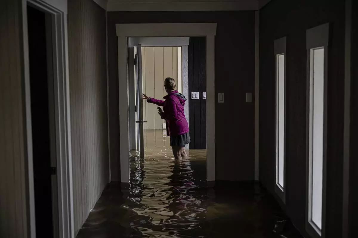 Carole Smith walks through her flooded home in Frankfort, Ky., April 5, 2025. (AP Photo/Jon Cherry)