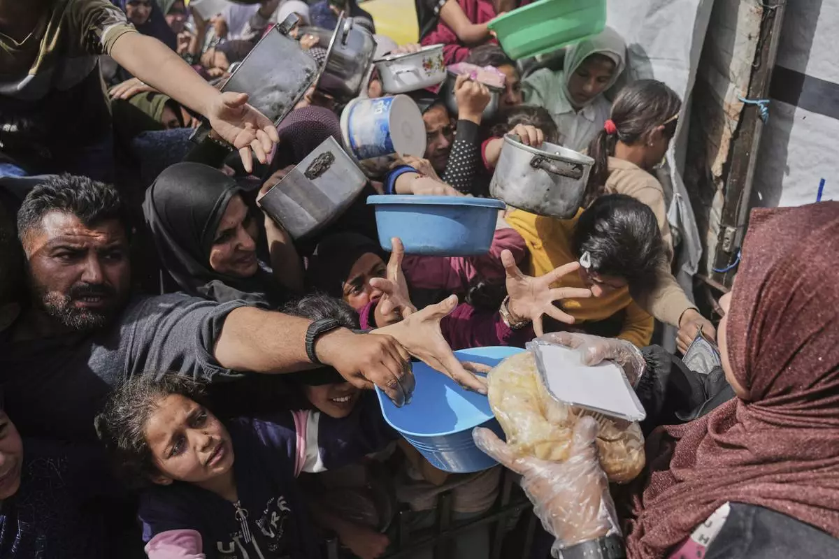 Palestinians clamber to receive donated food at a distribution center in Beit Lahiya in the northern Gaza Strip, April 7, 2025. (AP Photo/Jehad Alshrafi)