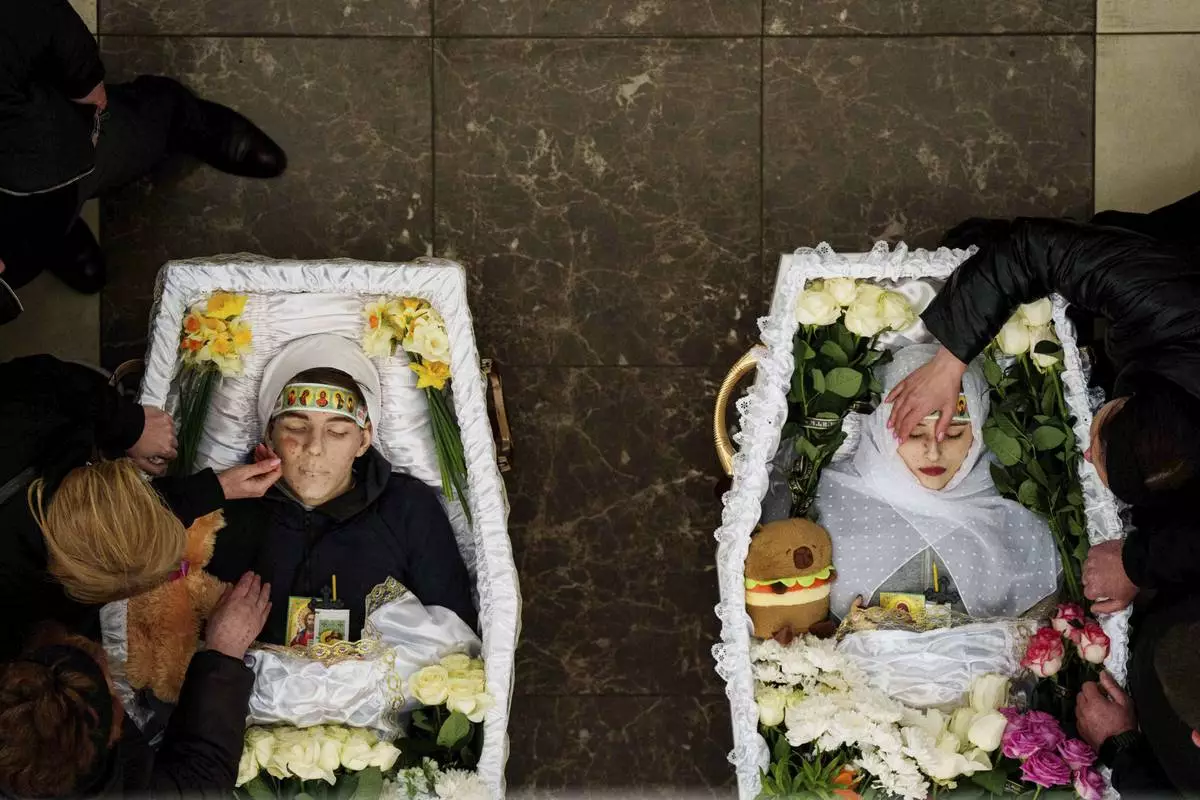 The mothers of Danylo Nikittskyi, 15, left, and Alina Kutsenko, 15, who were killed by a Russian missile, grieve as they pay their final respects during a funeral ceremony in Kryvyi Rih, Ukraine, April 7, 2025. (AP Photo/Evgeniy Maloletka)