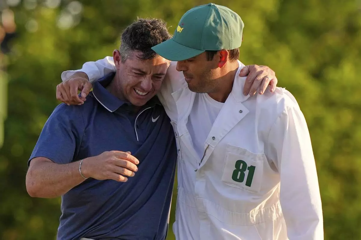 Rory McIlroy, of Northern Ireland, hugs caddie Harry Diamond, right, after winning in a playoff against Justin Rose, of England, after the final round the Masters golf tournament, Sunday, April 13, 2025, in Augusta, Ga. (AP Photo/David J. Phillip)