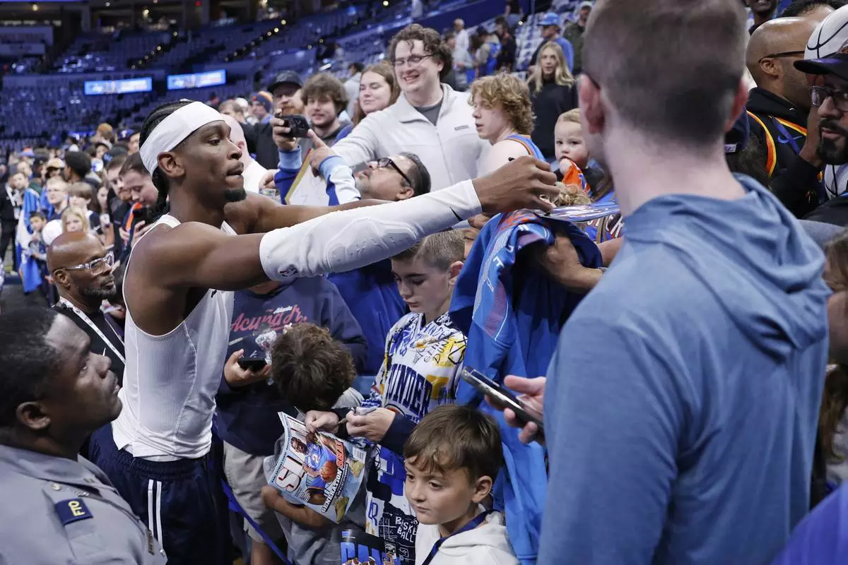 Oklahoma City Thunder guard Shai Gilgeous-Alexander, left, signs autographs for fans before Game 1 of an NBA first-round playoff series against the Memphis Grizzles, Sunday, April 20, 2025, in Oklahoma City. (AP Photo/Nate Billings)