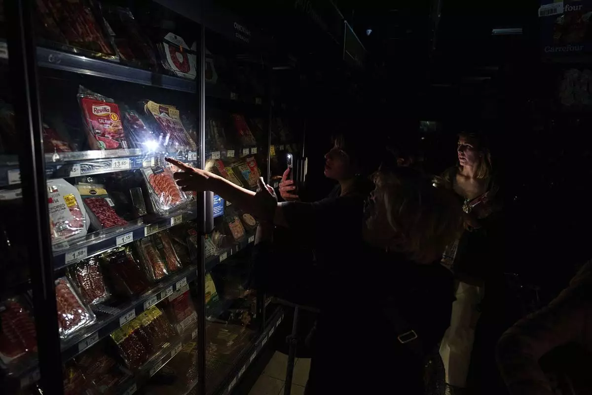 People buy food at a supermarket during a massive power outage in Pamplona, northern Spain, Monday, April 28, 2025. (AP Photo/Miguel Oses)
