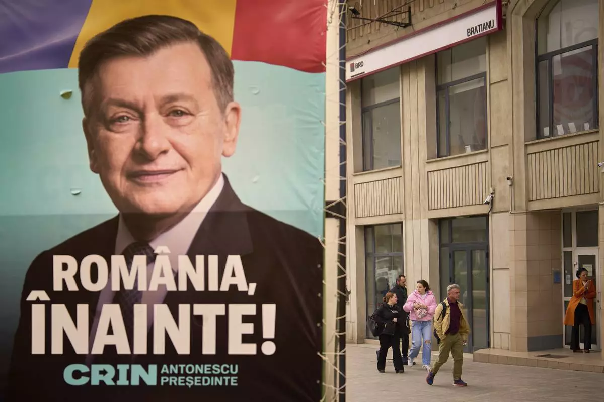 People walk by a poster of Crin Antonescu, the presidential candidate backed by Romania's governing coalition candidate in the upcoming May elections in Bucharest, Romania, Friday, March 28, 2025. (AP Photo/Vadim Ghirda)