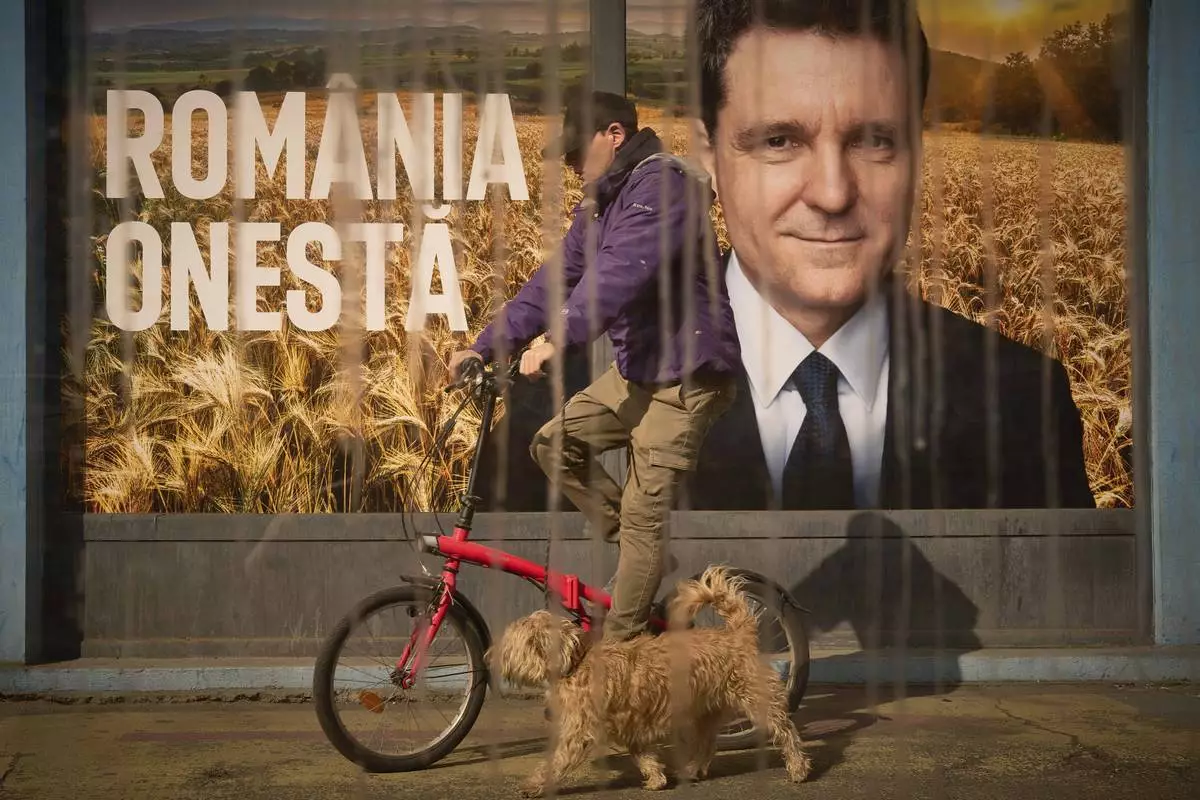A man and a dog pass by posters of Nicusor Dan, the mayor of Bucharest and presidential candidate in the upcoming May elections in Bucharest, Romania, Friday, March 28, 2025. (AP Photo/Vadim Ghirda)