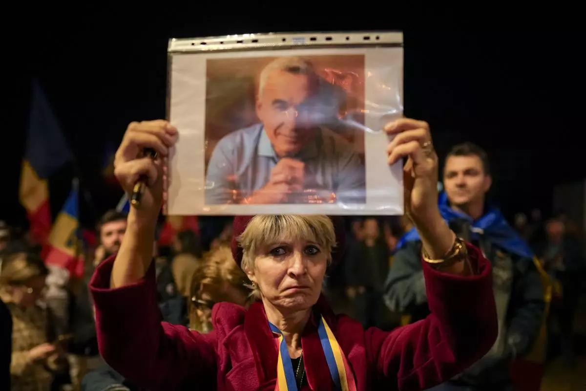 FILE - A woman holds a portrait of Calin Georgescu during a protest after Romania's Constitutional Court upheld a ban on his candidacy in the presidential election rerun, in Bucharest, Romania, Tuesday, March 11, 2025. (AP Photo/Vadim Ghirda. File)