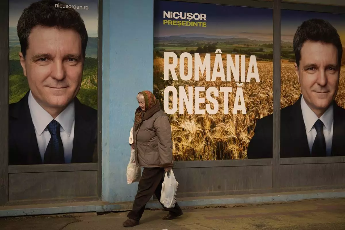 A woman walks by posters of Nicusor Dan, the mayor of Bucharest and presidential candidate in the upcoming May elections in Bucharest, Romania, Friday, March 28, 2025. (AP Photo/Vadim Ghirda)
