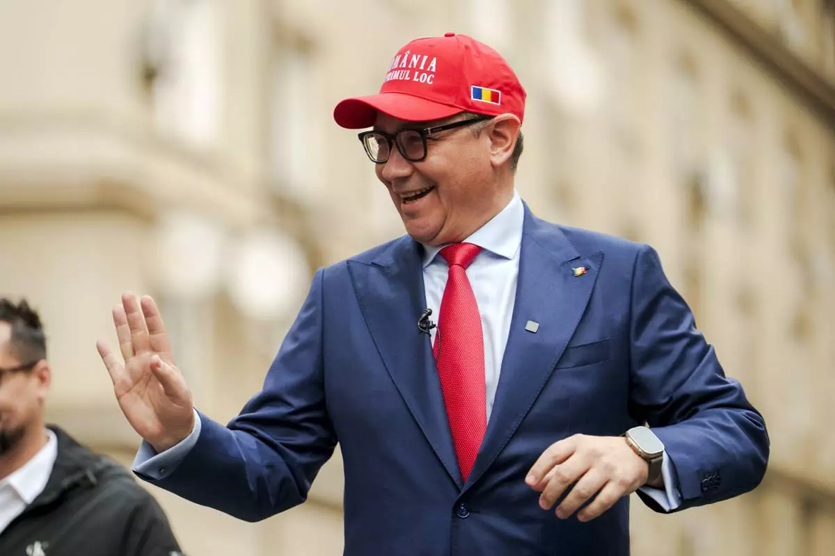 FILE - Victor Ponta, independent candidate in the upcoming presidential elections, wearing a cap that reads "Romania First" waves to supporters upon arriving to register his bid with the country's electoral authority in Bucharest, Romania, Wednesday, March 12, 2025. (AP Photo/Vadim Ghirda, File)
