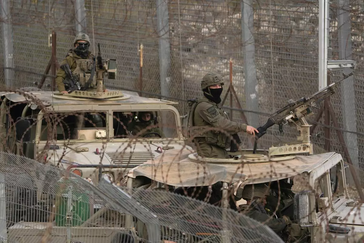 FILE - Israeli soldiers stand on armoured vehicles after crossing the security fence near the so-called Alpha Line that separates the Israeli-controlled Golan Heights from Syria, in the town of Majdal Shams, Dec. 21, 2024. (AP Photo/Matias Delacroix, File)