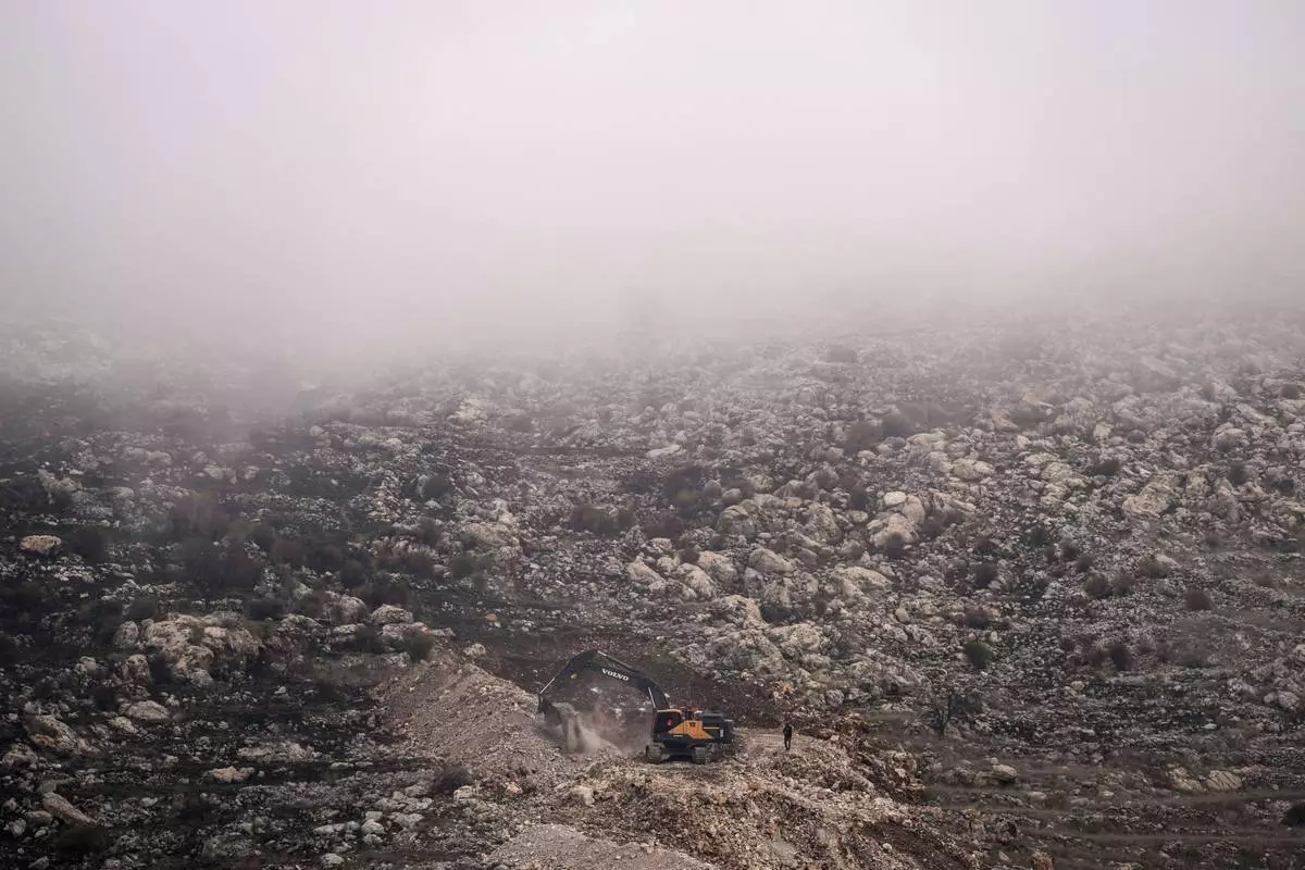 FILE - An Israeli bulldozer maneuvers on the buffer zone near the so-called Alpha Line that separates the Israeli-controlled Golan Heights from Syria, viewed from the town of Majdal Shams, Dec. 21, 2024. (AP Photo/Matias Delacroix, File)
