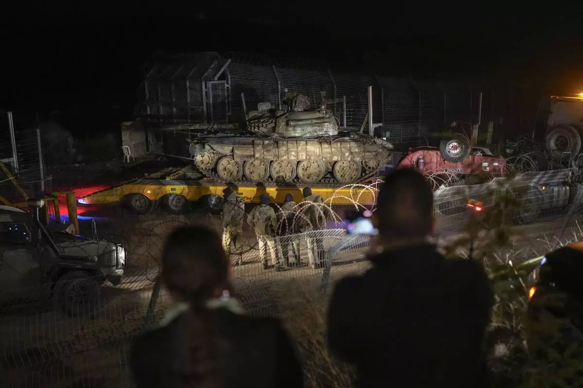 FILE - An Israeli truck carries a Syrian tank from the buffer zone near the so-called Alpha Line that separates the Israeli-controlled Golan Heights from Syria, viewed from the town of Majdal Shams, Dec. 21, 2024. (AP Photo/Matias Delacroix, File)
