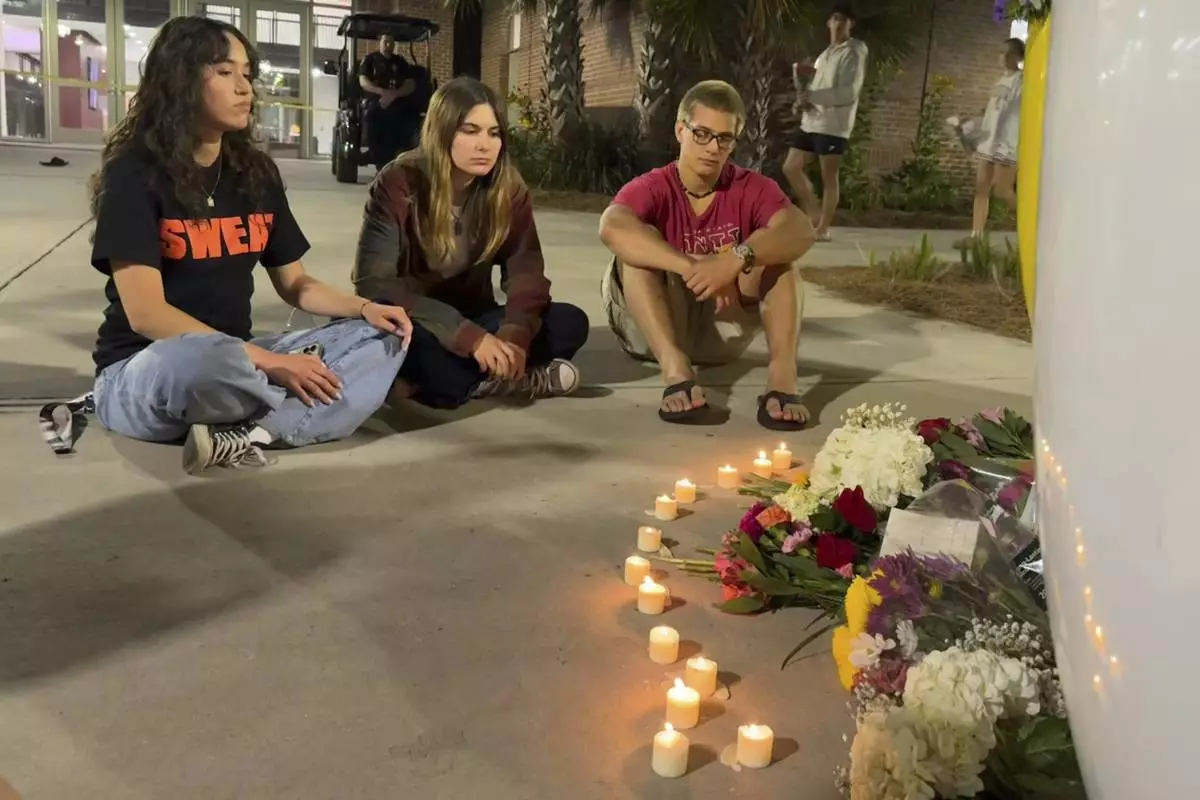 People sit in front of a makeshift memorial outside the student union at Florida State University, Thursday, April 17, 2025, in Tallahassee, Fla., following a campus shooting. (AP Photo/Kate Payne)