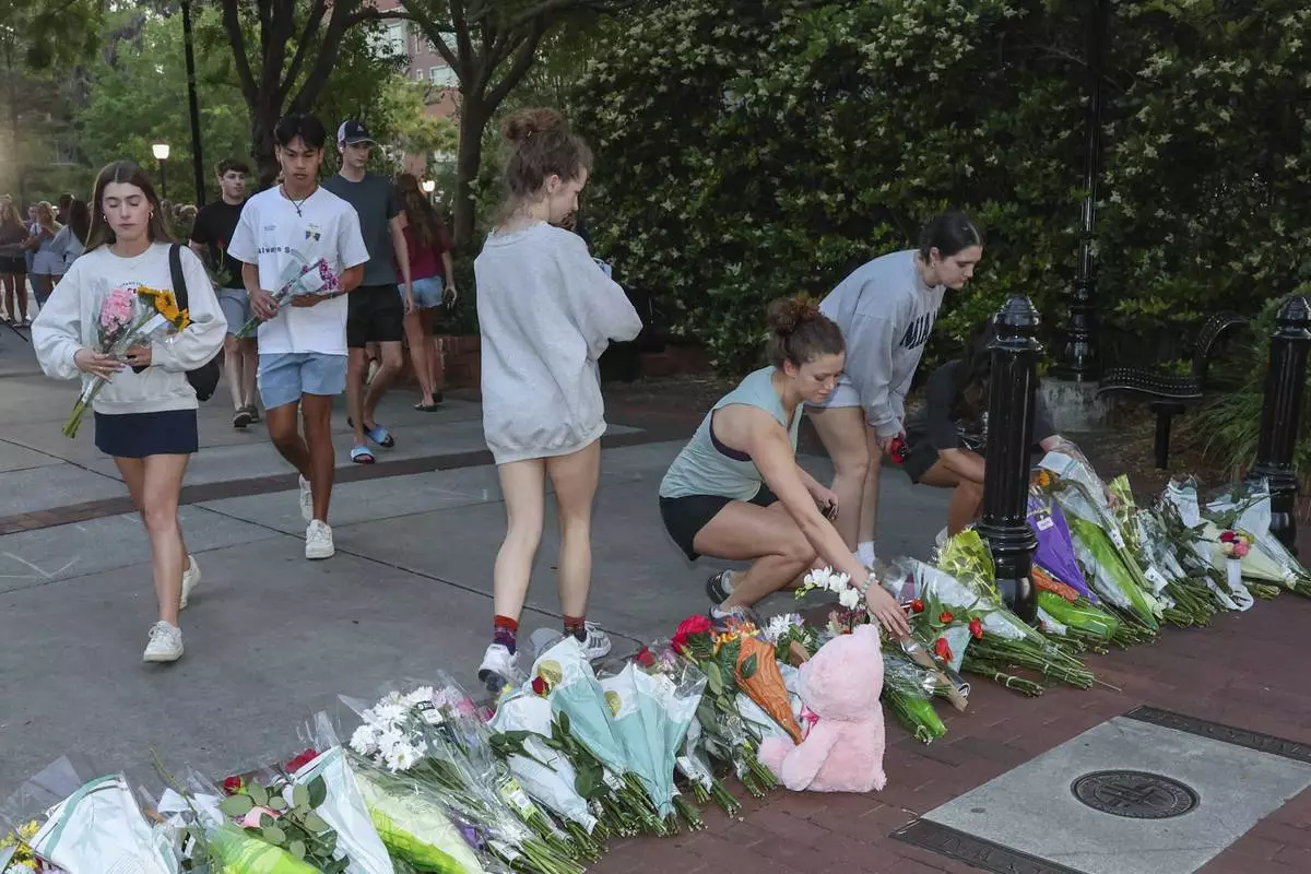 An impromptu memorial shared online brings students bearing flowers near the center of the Florida State campus in sight of the Student Union building, Tallahassee, Fla., Thursday, April 17, 2025. (AP Photo/Gary McCullough)